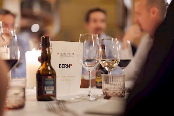 Detailaufnahme der gedeckten Tafel mit VSTM Programm und Weingläsern – Eventfotografie im Kornhauskeller Bern.