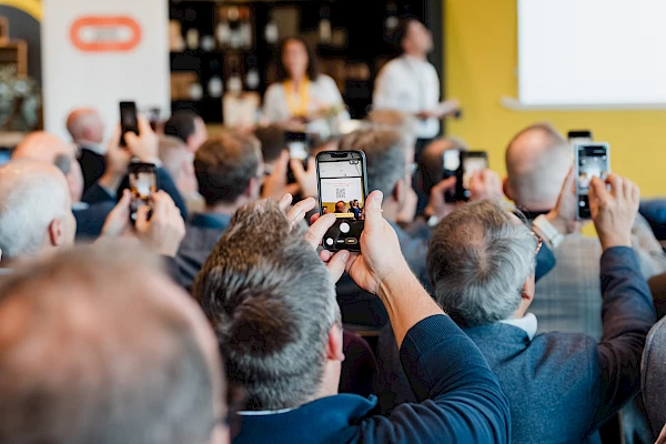 Teilnehmer fotografieren die Präsentation beim Business-Event in Bern mit ihren Smartphones.